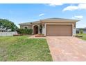 Inviting single-story home with a brick driveway, attached garage, and a neatly landscaped front yard at 5515 Windsong Oak Dr, Leesburg, FL 34748