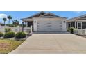 Exterior view of a well-maintained home with a two-car garage and lush landscaping along the driveway at 6223 Atkinson Ln, The Villages, FL 32163