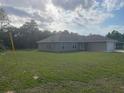 Single story house with light colored stucco, a 2 car garage, and a green lawn at 74 Malauka Pass, Ocklawaha, FL 32179