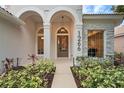 Elegant front entrance with decorative columns, a hanging light fixture, and landscaped garden beds at 1266 Saint Albans Loop, Lake Mary, FL 32746