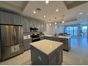 Modern kitchen features stainless steel appliances, gray cabinetry, and a center island with quartz countertops at 16300 County Road 455 # 703, Montverde, FL 34756