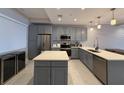 This kitchen has gray cabinets, a stainless steel refrigerator, and an island with a white countertop at 16300 County Road 455 # 703, Montverde, FL 34756