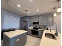 Modern kitchen with gray cabinets, stainless steel appliances, and island with white countertop at 16300 County Road 455 # 703, Montverde, FL 34756