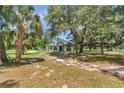Home with mature landscaping, palm trees, and green lawn, showcasing the well-maintained exterior at 16758 Ne 135Th Ave, Fort Mc Coy, FL 32134