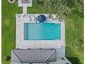 Aerial view of a sparkling pool surrounded by a stone patio, lounge chairs, and an umbrella at 3865 W Stillwood Ln, Lake Mary, FL 32746