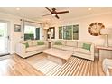 Bright living room with hardwood floors, large windows and neutral-colored sofas with a stylish ceiling fan at 507 N Peninsula Ave, New Smyrna Beach, FL 32169
