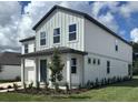 Beautiful two-story home with inviting covered porch, gray siding, and lush green lawn at 710 Junonia Blvd, New Smyrna Beach, FL 32168