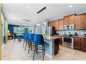 Open concept kitchen with stainless appliances, granite counters, breakfast bar, and pendant lights at 7521 Marker Ave, Kissimmee, FL 34747