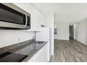 Well-equipped kitchen featuring granite countertops, white cabinets, and stainless steel microwave at 935 S Atlantic Ave # 302, Daytona Beach, FL 32118