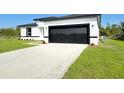 Modern home featuring a black garage door, sleek white exterior and newly planted landscaping at 2336 Sw 168Th Loop, Ocala, FL 34473
