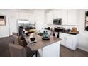 Modern eat-in kitchen boasts stainless steel appliances, white cabinetry, and a stone-topped island at 314 Puma Loop, Groveland, FL 34736