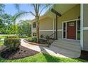 Inviting front entrance with a red door, tiled steps, and lush landscaping on a sunny day at 33925 Highland Rd, Leesburg, FL 34788