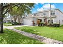 Side view of two-story house featuring a two-car garage and landscaped front yard at 4785 Cumbrian Lakes Dr, Kissimmee, FL 34746