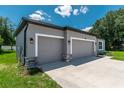 Attached three-car garage featuring gray doors, stone accents, and modern lighting fixtures at 506 Marion Oaks Trl, Ocala, FL 34473