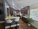 Modern kitchen featuring dark wood cabinets, white countertops, stainless steel appliances, and bar stool seating at 6436 Fig Leaf St, Magnolia Square, FL 34771
