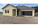 Exterior of home construction shows the structure with a two-car garage and a yard with dirt at 706 Junonia Blvd, New Smyrna Beach, FL 32168