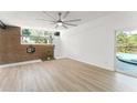Bright living room featuring wood floors, brick wall, and access to the pool area at 7712 Hoosier Pl, Orlando, FL 32807