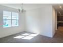 Bright dining room with a chandelier, carpet floors, and natural sunlight from a large window at 7779 Trapani Loop, Clermont, FL 34714
