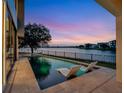 Inviting pool with in-water loungers overlooking a tranquil lake at sunset at 8157 Elion St, Orlando, FL 32827