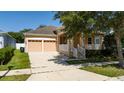 Charming tan home featuring a two-car garage and a quaint porch with white railing, perfect for relaxing at 10076 Kimble Field Way, Orlando, FL 32827