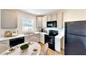 Modern kitchen featuring white cabinets, black appliances, and a breakfast nook, complemented by natural light at 1114 Camden W Way, Poinciana, FL 34758