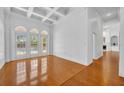 Bright living room with hardwood floors, coffered ceiling, and arched windows overlooking pool at 1158 Sweet Heather Ln, Apopka, FL 32712