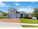 Well-maintained two-story house with a three-car garage, brick paved driveway, and lush green lawn at 1265 Blarney St, Minneola, FL 34715