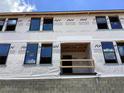 Townhome construction featuring multiple windows and sturdy block foundation, covered in Ashton Woods branded wrap at 15465 Hamlin Park Drive, Winter Garden, FL 34787