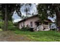 Charming single-story home with a covered porch and white trim, surrounded by lush greenery and trees at 1996 Indiana Ave, Winter Park, FL 32789