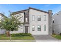 Modern two-story home featuring a stone accent wall, gray trim, and a paver driveway at 2927 Fable St, Kissimmee, FL 34746