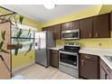 Kitchen features stainless appliances, brown cabinets, ample counter space, and natural light at 3475 Flossmoor Ave # 103, Orlando, FL 32822