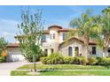 Stately home features a stone turret, tile roof, manicured landscaping, and a side entry two-car garage at 3844 Bowfin Trl, Kissimmee, FL 34746