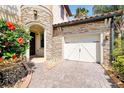 Attached garage with a paved driveway, stone accents, and professional landscaping at 3844 Bowfin Trl, Kissimmee, FL 34746