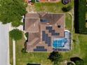 Aerial view of a home with solar panels on the roof and a screened-in pool at 887 Lancer Cir, Ocoee, FL 34761