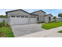 Paver driveway leading to a white brick home with a two-car garage and manicured front yard at 9265 Eagles Perch Pl, Orlando, FL 32825