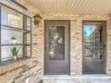 Close-up of a brick-clad townhouse facade with a dark gray door, window, and overhead lantern at 1748 Foxhall Cir # 1748, Kissimmee, FL 34741