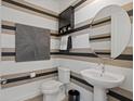 Stylish powder room with a pedestal sink, round mirror, and eye-catching striped wallpaper at 2054 Education St, St Cloud, FL 34771