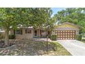 Inviting single-story brick home with brown shutters, a well-manicured lawn, and a large shade tree at 244 Angeles Rd, Debary, FL 32713