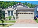 Charming home features a two-car garage, brick driveway, manicured landscaping, and a well-maintained lawn at 2456 Varenna Loop, Kissimmee, FL 34741