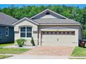 Charming home features a two-car garage, brick driveway, manicured landscaping, and a well-maintained lawn at 2456 Varenna Loop, Kissimmee, FL 34741