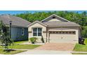 Charming home features a two-car garage, brick driveway, manicured landscaping, and a well-maintained lawn at 2456 Varenna Loop, Kissimmee, FL 34741