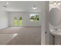 Bright living room boasts neutral carpet, white walls, natural light, and adjoined half bathroom at 3435 Vesara Dr, Davenport, FL 33837