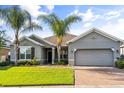 Attractive one-story home with green lawn, a brick driveway, gray exterior and decorative palm trees at 3925 Green Sabal Dr, Orlando, FL 32824