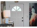 Bright entryway features a white door with decorative glass and a stylish console table with marble lamp and art at 7 Westchester Dr, Kissimmee, FL 34744