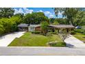 Charming brick home with a screened lanai, lush landscaping, and convenient carport at 7 Westchester Dr, Kissimmee, FL 34744
