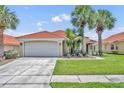 Well-maintained home featuring a red tile roof, a two-car garage, and a lush lawn, enhanced by swaying palm trees at 112 Cordova Ave, Davenport, FL 33897