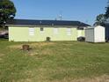 Expansive backyard featuring a well-manicured lawn, storage shed and a modern black metal roof at 410 5Th S St, Dundee, FL 33838