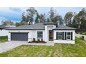 A beautiful single Gathering home with manicured lawn, a paved driveway, and a modern white and gray exterior at 5110 Sw 158Th St, Ocala, FL 34473