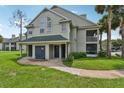 Inviting townhouse exterior with a garage, charming entryway, and lush green lawn at 6088 Westgate Dr # 201, Orlando, FL 32835