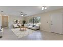 Bright living room with neutral tones, tile floors, a ceiling fan, and a modern white sofa near large windows at 622 N Goodrich Dr, Deltona, FL 32725